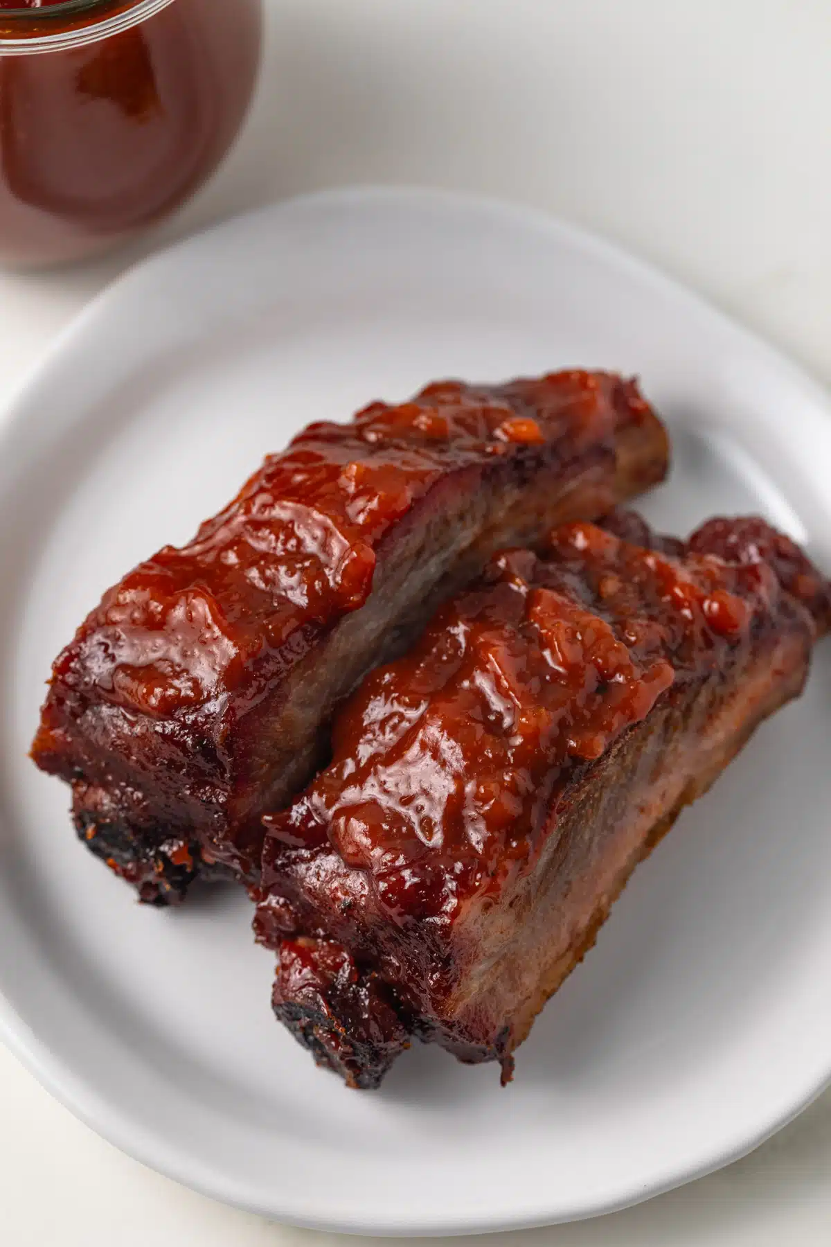 Two ribs with apple bbq sauce on white plate.