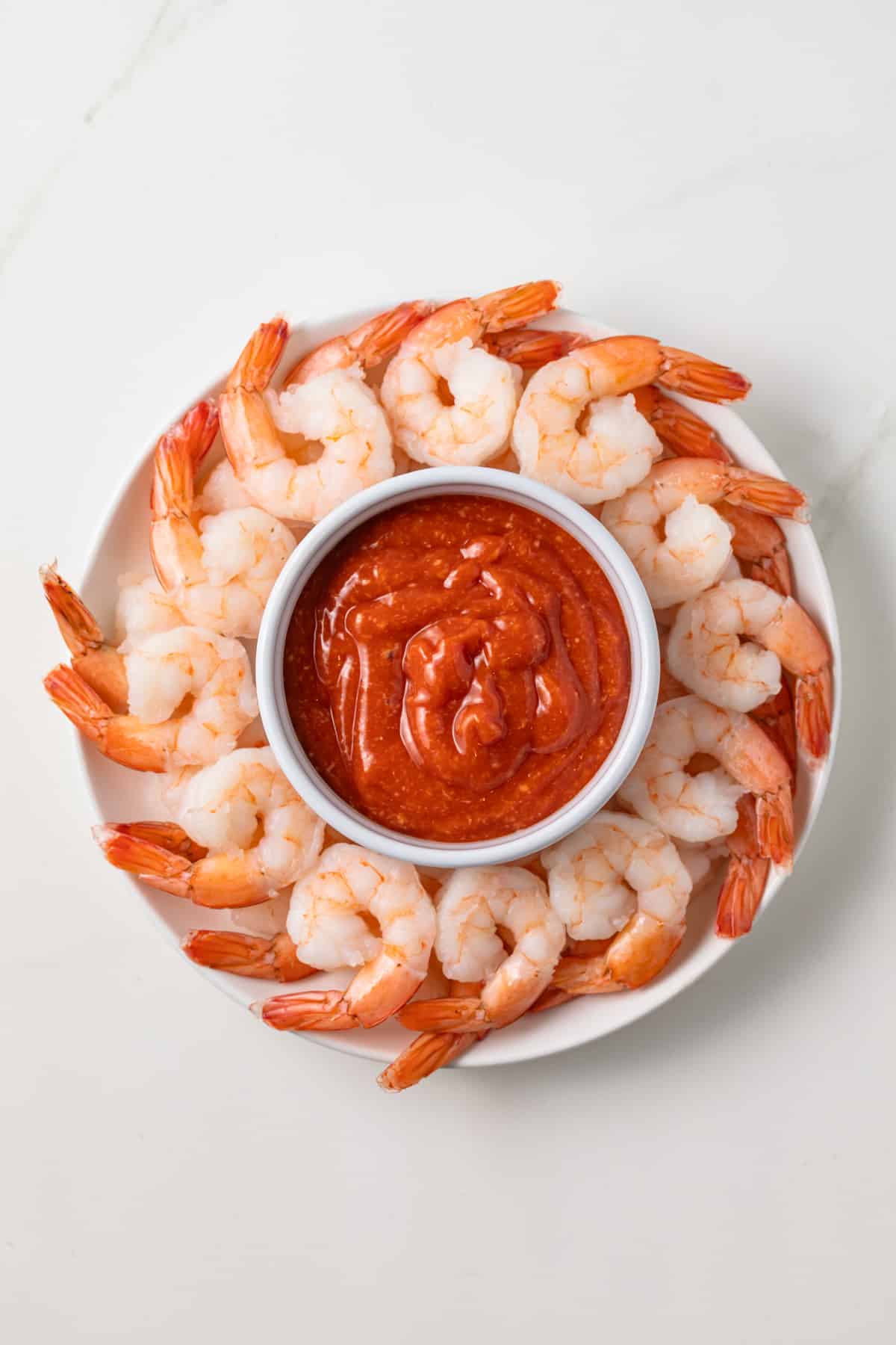 Bowl of cocktail sauce with steamed shrimp.