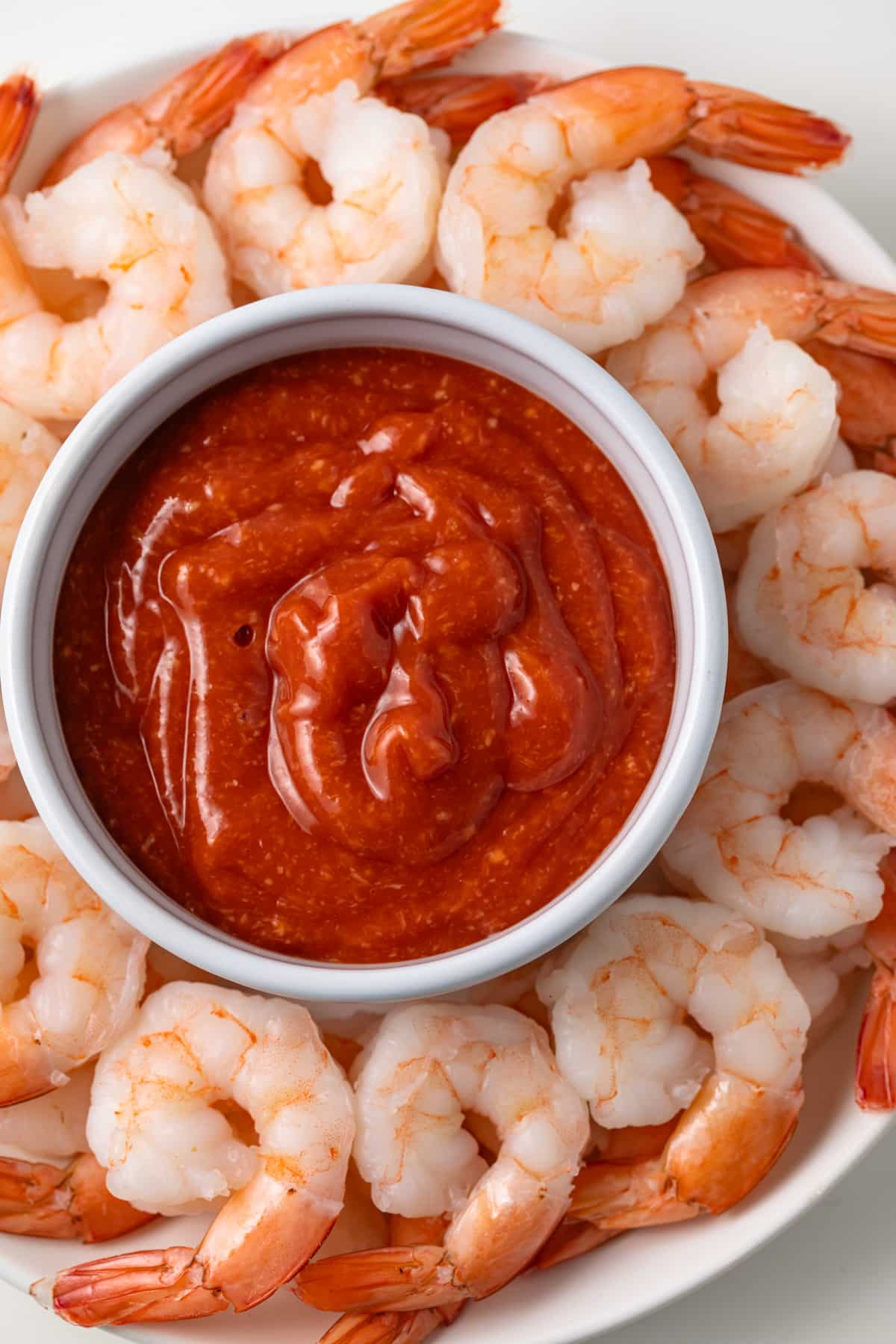 Close up of bowl of cocktail sauce with steamed shrimp.