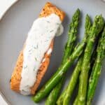 Overhead of salmon topped with lemon dill sauce and side of asparagus.