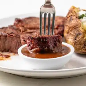 Bite of steak dipped in sauce.
