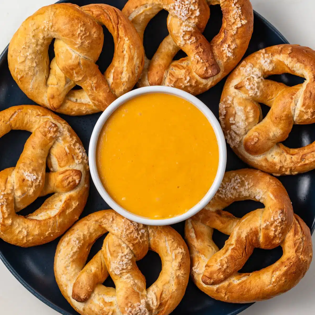 Overhead view of bowl of beer cheese surrounded by pretzels.