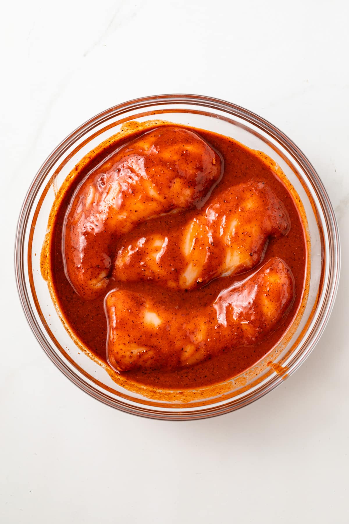 Al pastor marinated chicken in glass bowl.