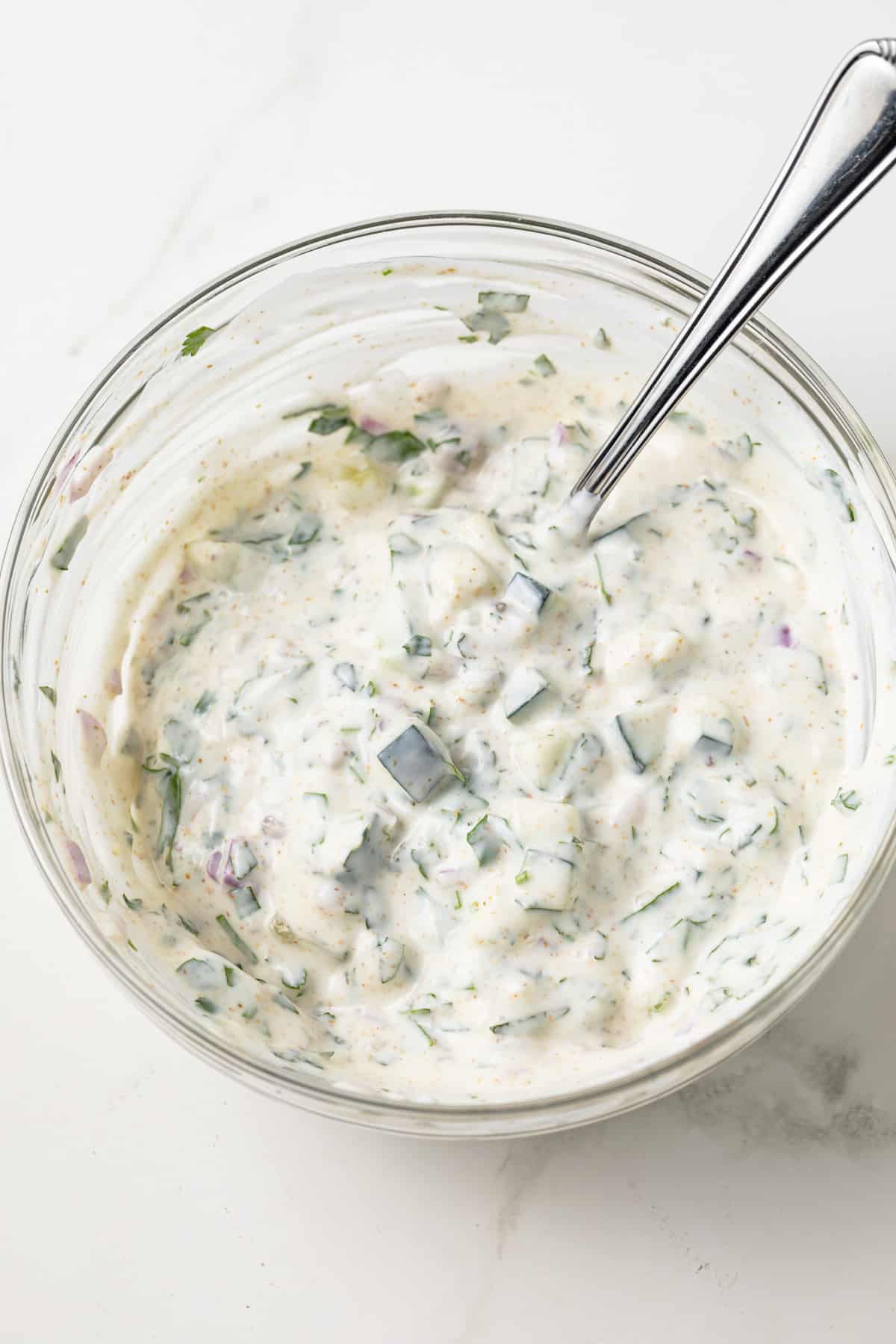 Raita in mixed in glass bowl.
