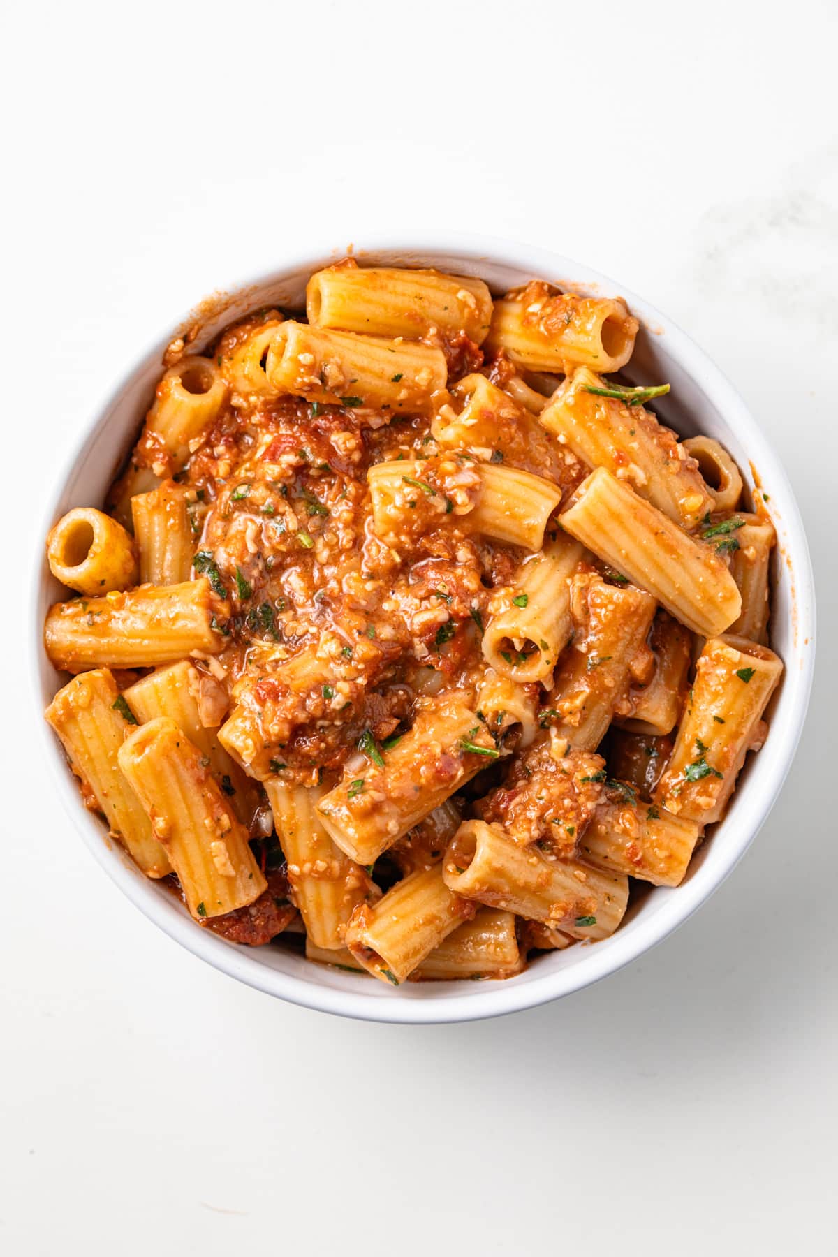 Sun dried tomato pesto over pasta in a bowl.