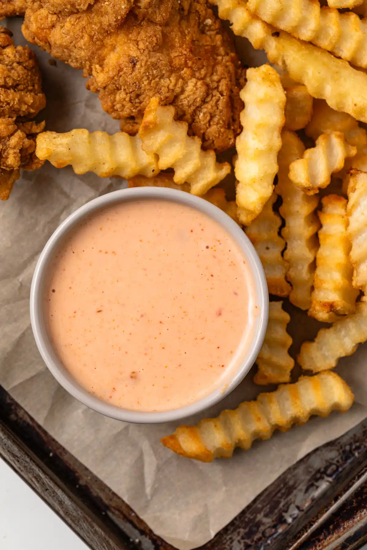 Bowl of boom boom sauce with fries and chicken tenders.