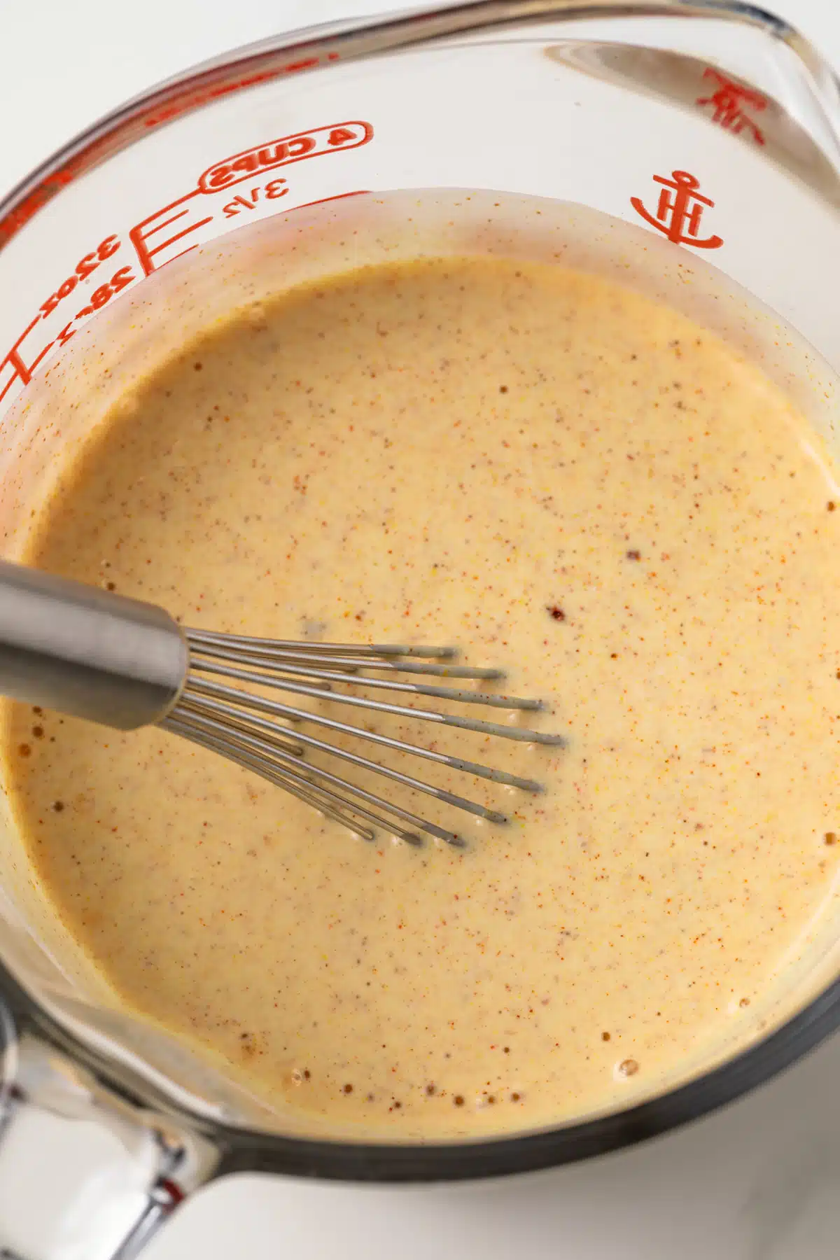 Buttermilk chicken marinade in glass measuring cup.