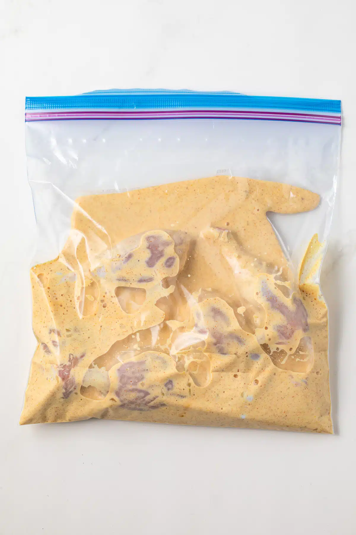 Buttermilk chicken marinade and chicken drumsticks in ziptop bag.