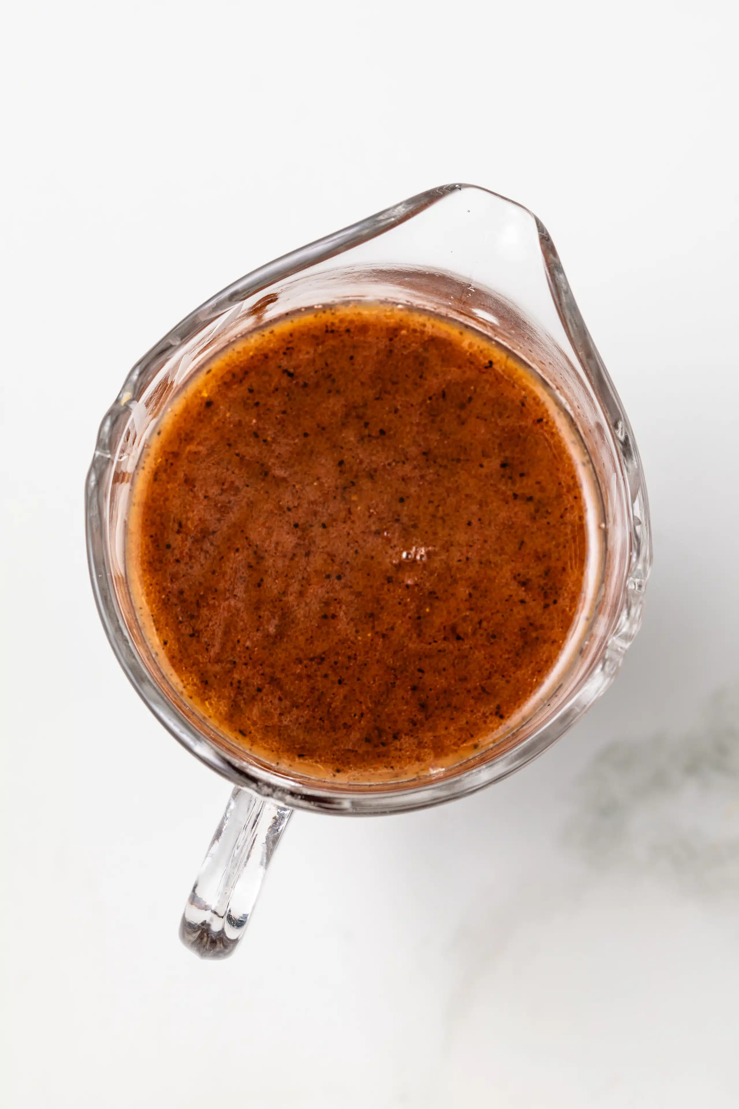 Overhead of bordelaise sauce in glass gravy boat.