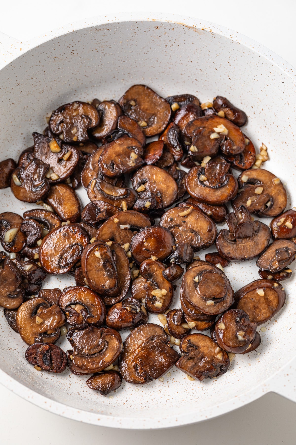 Sauteed mushrooms with garlic in fry pan.