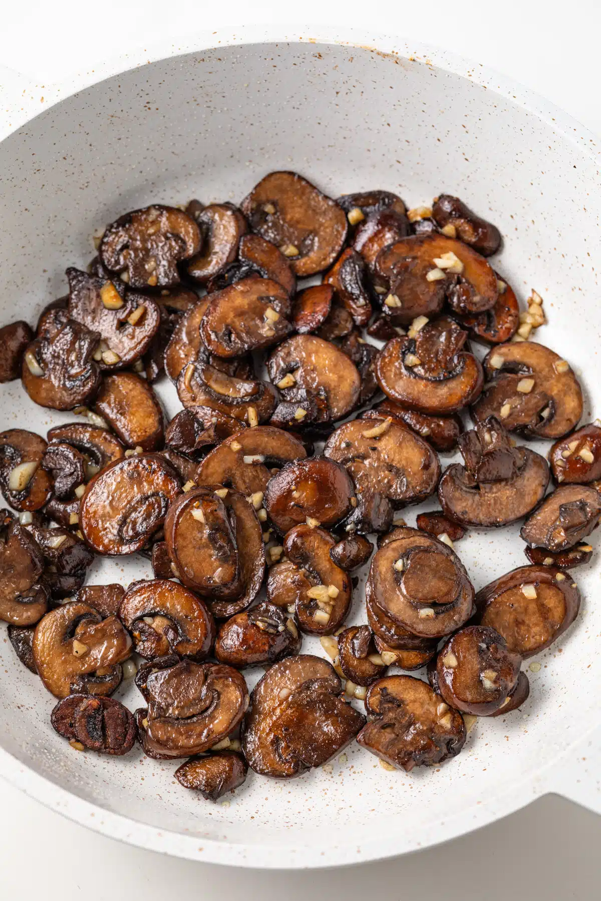Sauteed mushrooms with garlic in fry pan.