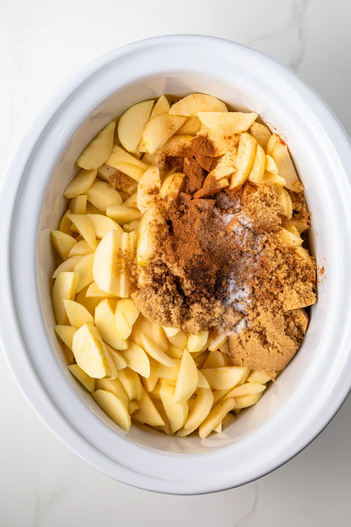 Apples with spices and sugar in a slow cooker.