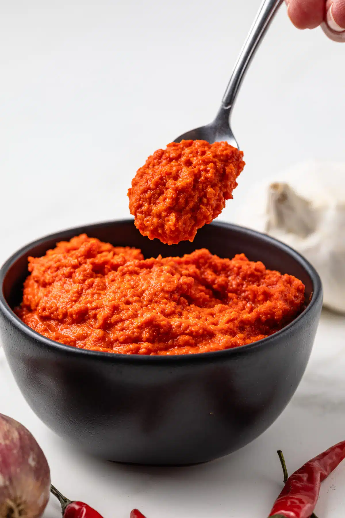 Side view of sambal oelek in a bowl with a spoon.
