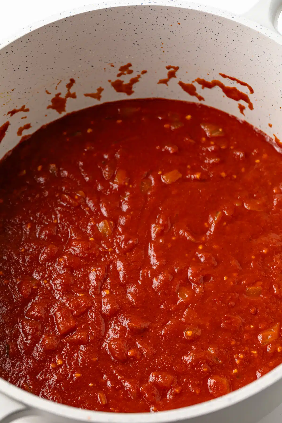 Tomato sauce added to sauteed onions in a pot.