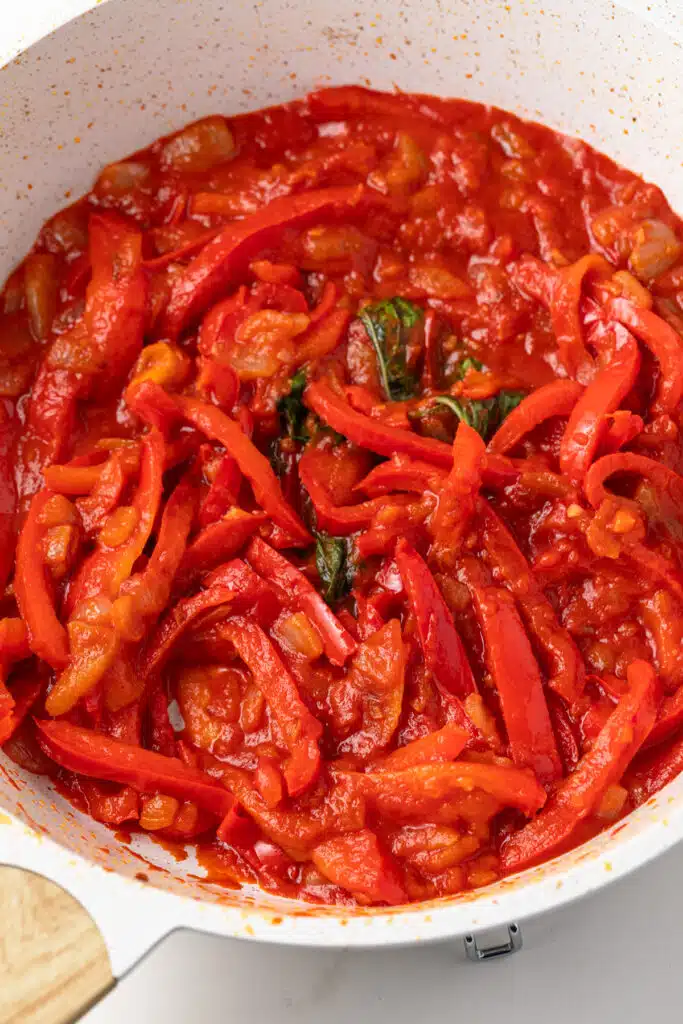 Peppers, onion, garlic, and tomato sauce in a fry pan.