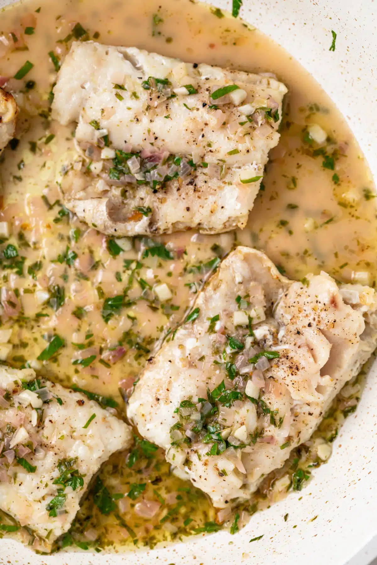 Close up of fish in pan sauce.