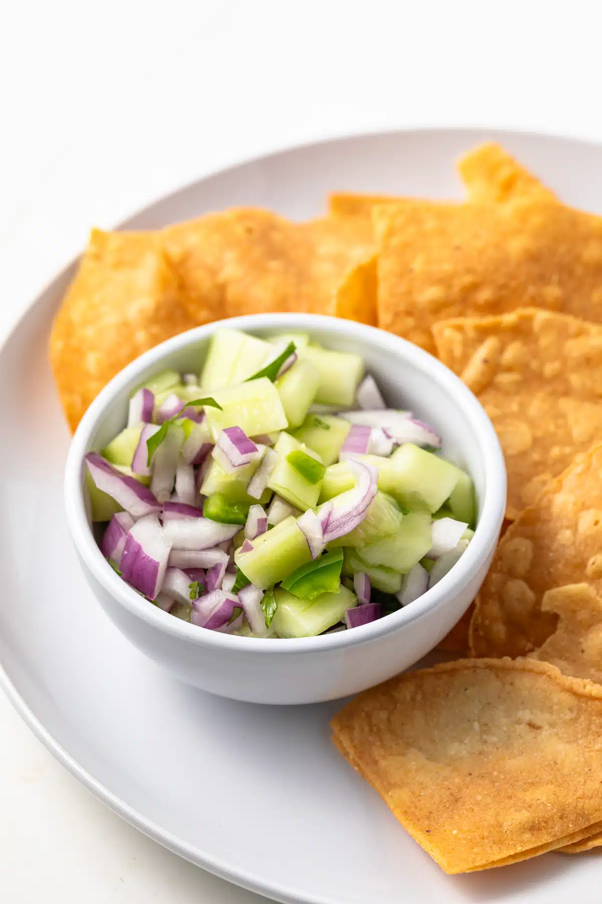 Side view of cucumber jalapeno salsa in a white bowl.