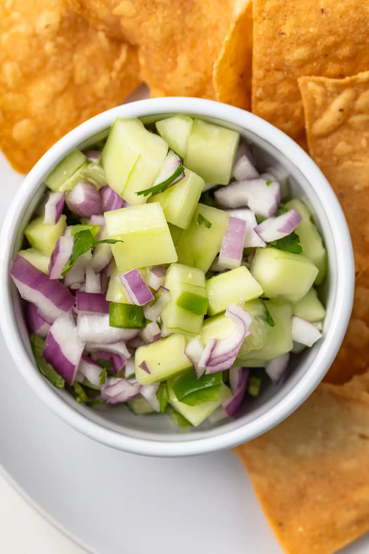 Overhead view of cucumber jalapeno salsa in a white bowl.