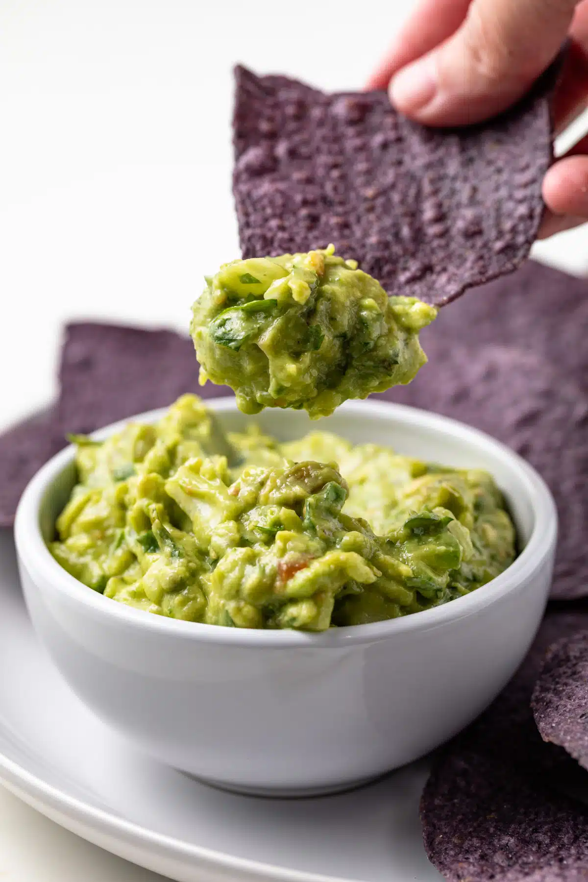 Tortilla chip scooping up slasa verde guacamole.