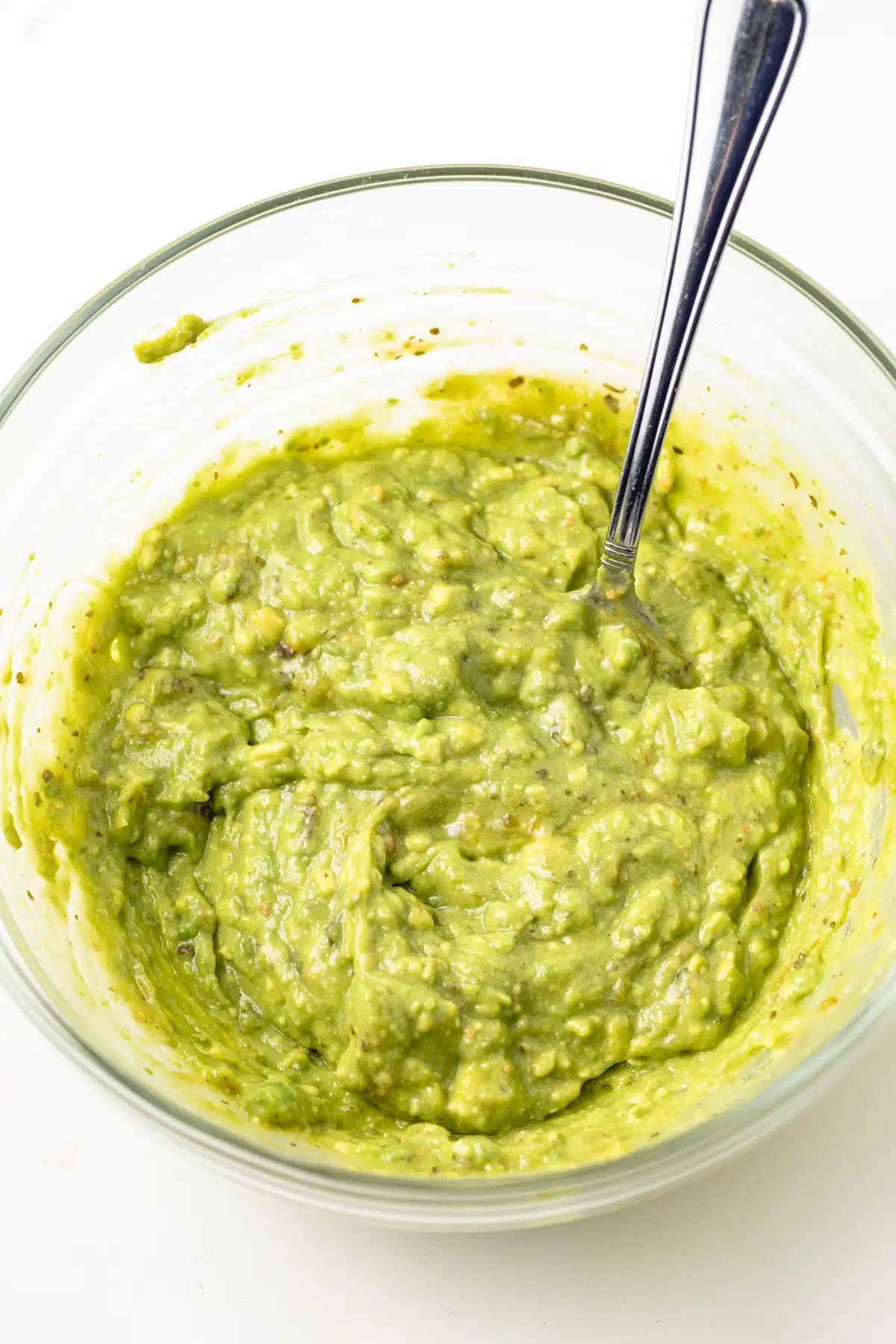 Smashed avocado in a glass bowl.