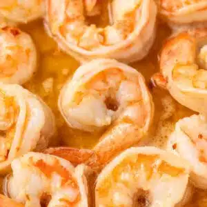 Close up of shrimp coated in scampi sauce.
