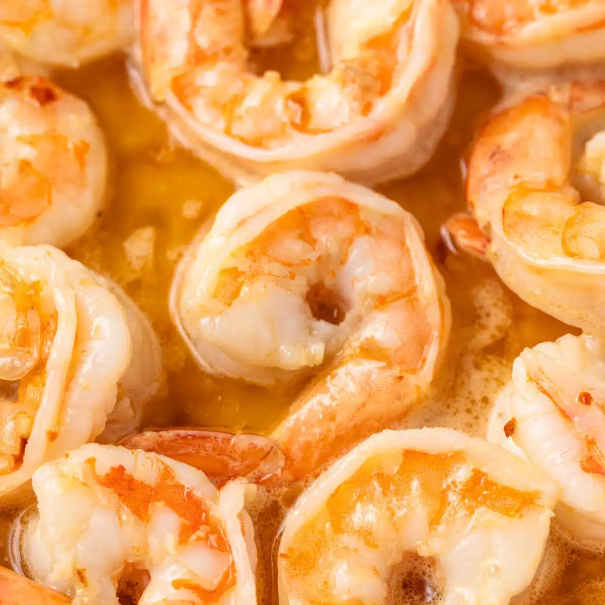 Close up of shrimp coated in scampi sauce.