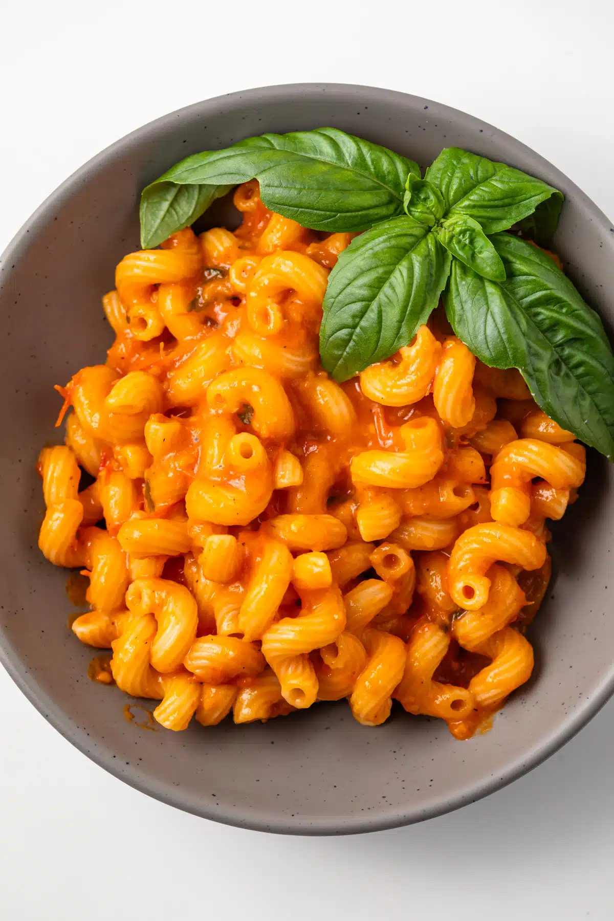 Overhead view of pasta coated in roasted tomato cherry sauce in a bowl.