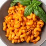 Overhead view of pasta coated in roasted tomato cherry sauce in a bowl.