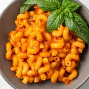 Overhead view of pasta coated in roasted tomato cherry sauce in a bowl.