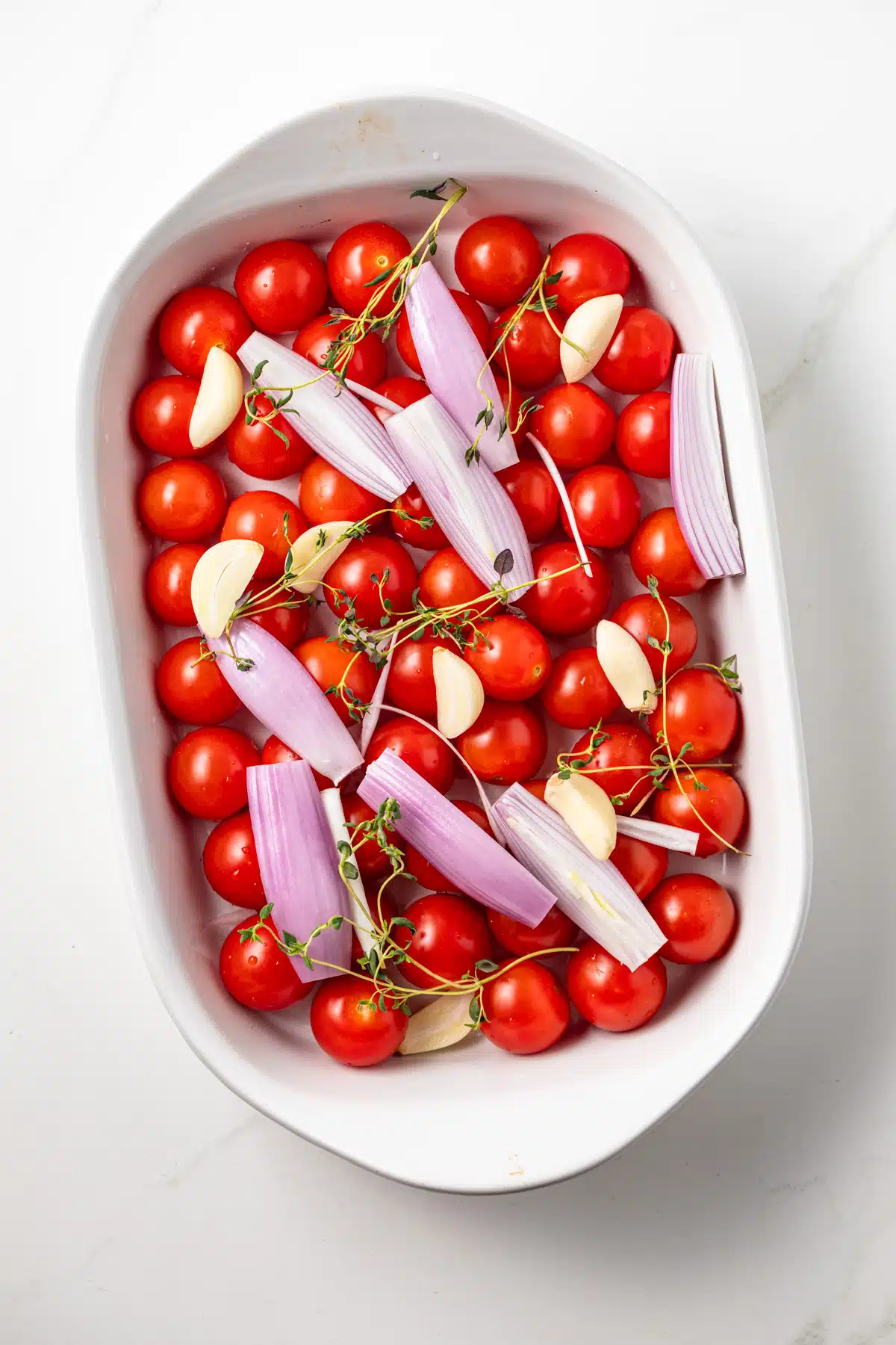 Tomatoes, shallots, and garlic in a roasting pan.